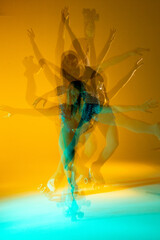 Dancing young mixed race girl enjoying moving in colorful neon studio light. Long exposure. woman...
