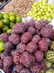 Purple custard apples, cherimoya fruit, amla and peanuts, asian sweet dessert, healthy food on the market, fruit stall.