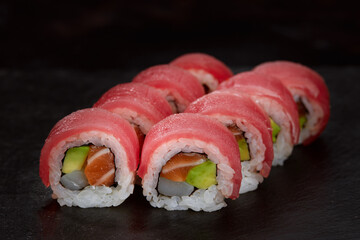 Sushi roll Maguro with tuna, shrimp, salmon, smoked eel, avocado, philadelphia cheese on black background. Sushi menu. Japanese food.
