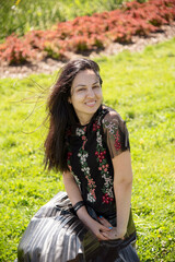 portrait of smiling brunette woman on green grass in summer  in a park