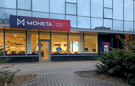 Moneta Money Bank with ATM and lights on in evening