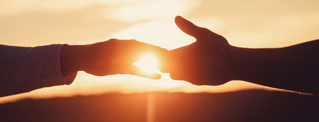 Giving a helping hand. Rescue, helping gesture or hands. Two hands silhouette on sky background,...