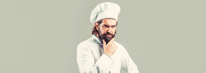 Serious cook in white uniform, chef hat. Portrait of a serious chef cook. Bearded chef, cooks or...