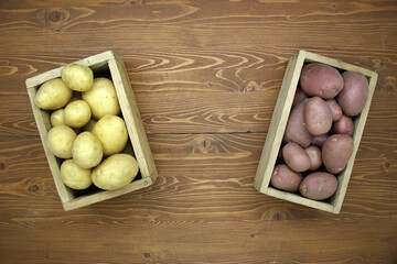 Red and yellow fresh potatoes on a wooden background