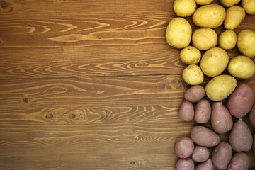 Fototapeta na wymiar Red and yellow fresh potatoes on a wooden background