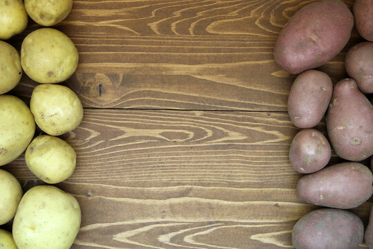 Red And Yellow Fresh Potatoes On A Wooden Background