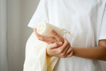A teenage girl holds a towel and loofah in her hands. Taking care of the body.
