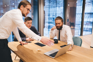 Businesspeople discussing project while looking at laptop screen in office