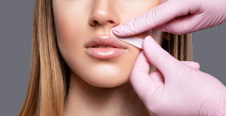 The beautician makes a mustache removal with wax in a young woman. hair removal procedure on a woman’s body.