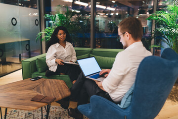 Man working on computer against female colleague in workplace