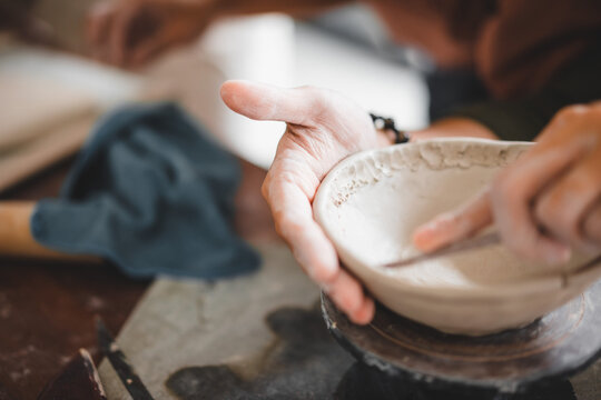 View of male hands works with clay makes future ceramic plate, ceramic artist makes classes of hand building in modern pottery workshop, creative people handcrafted design