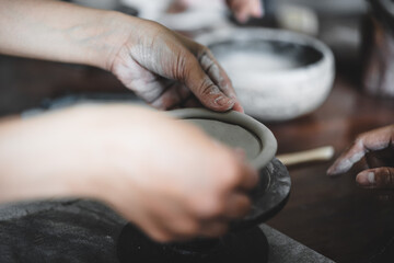 View of female hands works with clay makes future ceramic plate, ceramic artist makes classes of hand building in modern pottery workshop, creative people handcrafted design