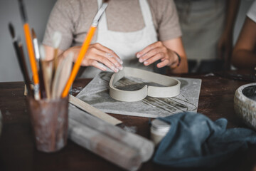 View of female hands works with clay makes future ceramic plate, ceramic artist makes classes of hand building in modern pottery workshop, creative people handcrafted design