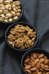 Vegetarian foods, seeds and nutrienents in almonds, walnuts and pistachios in three different bowls aligned.
