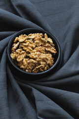 Perspective view of a bowl with walnuts over a twisted tablecloth.
