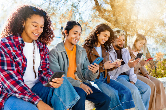Group of multiracial friends watching smart mobile phones - Teenagers addiction to new technology trends - Concept of youth, tech, social and friendship - Cheerfuel young students smiling smartphone
