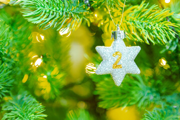 ein glitzernder Stern am Weihnachtsbaum mit einer Zahl (2) für einen Kalender