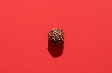 Chocolate truffle minimalist on a red background in bright light