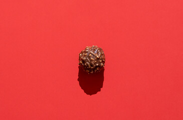 Naklejka premium Chocolate truffle minimalist on a red background in bright light