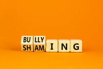 Shaming and bullying symbol. Concept words Shaming and Bullying on wooden cubes. Beautiful orange table orange background. Business shaming and bullying concept. Copy space.