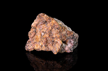 A fragment of the mineral granite with a granular structure. Reddish stone with white and black patches