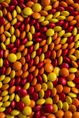 Red, orange, and yellow candy coated chocolate button sprinkle texture - M&Ms, Smarties, sprinkles