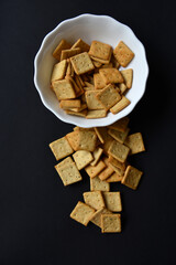 Delicious peppery cookies in a white plate on a black background.