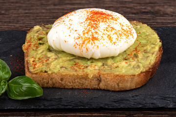 Avocado toast with poached egg on a stone board for serving.