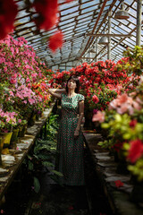 A girl in a green dress among a blooming garden of azaleas