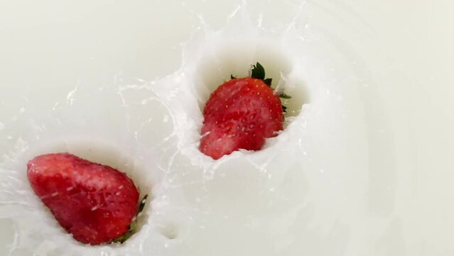 fresh strawberry falling into milk
