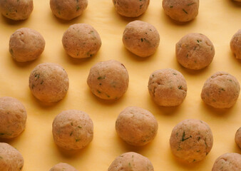 Close-up of frozen meatballs on a yellow background.
Semi-finished products for homemade meatballs from chicken with spices.
