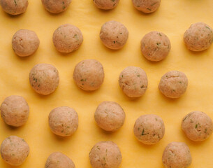 Semi-finished products for homemade meatballs from chicken with spices. Raw frozen meatballs on a yellow background.