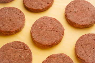 Large raw frozen cutlets of dark meat on a yellow background. Semi-finished products for grilling