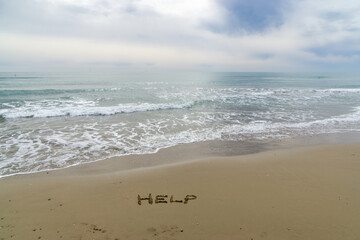 Fototapeta na wymiar Words Written in the sand. The word HELP written in the sand with the ocean in the background.
