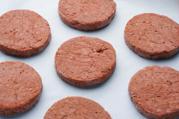 Large raw frozen meat patties on a blue background. Semi-finished products for home cooking