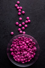 Pink candy coated chocolate button sprinkles in a bowl on dark slate - M&Ms, Smarties, sprinkles