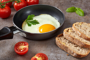 Little pan with a fried egg, bread and cherry tomatoes