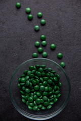 Green candy coated chocolate button sprinkles in a bowl on dark slate - M&Ms, Smarties, sprinkles