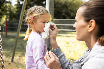 Fototapeta premium Mother blowing her child's nose. Child allergy, catching a cold, flu concept