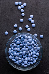 Blue candy coated chocolate button sprinkles in a bowl on slate - M&Ms, Smarties, sprinkles