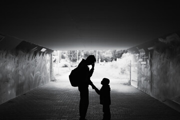 Tired , sad, stressed single father parent taking care of child standing in a dark city street....