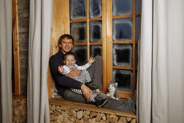 Father and son are sitting on the windowsill on the background of the window
