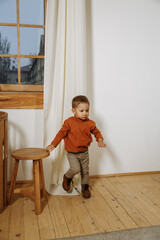 A little boy plays with toys at home against the background of a Christmas tree