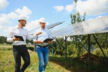 Two engineers are conducting outdoor inspection of solar photovoltaic panels