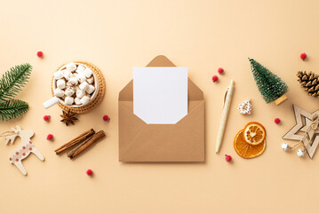 Christmas concept. Top view photo of open envelope with letter pen wood ornaments pine branch cone mug of cocoa mistletoe dried orange slices and cinnamon on isolated beige background with blank space