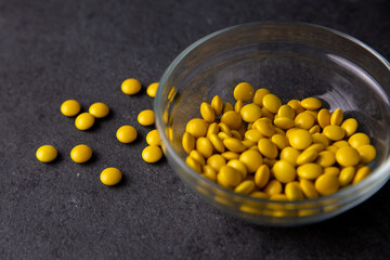 Yellow candy coated chocolate button sprinkles in a bowl on dark slate - M&Ms, Smarties, sprinkles