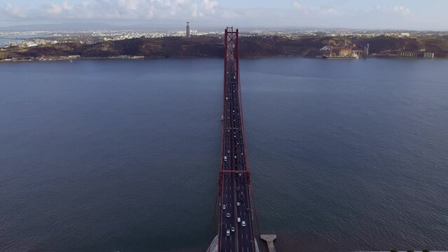 Aerial view of 25 de Abril bridge over the Tagus River at sunset in Lisbon, Portugal. Cinematic 4K