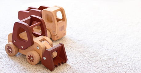 Selective focus on wooden cars bulldozer and truck in natural colors on a white cotton carpet. Environmentally friendly, plastic free toys for toddler. Eco concept. Space for text