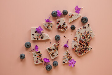 pink handmade chocolate with berries and flowers. Broken bars with hazelnuts, almond and raspberry