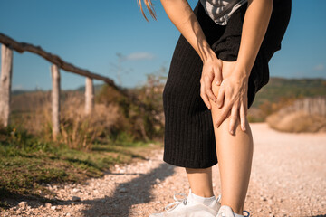 Girl massaging his knees after running in the hills. She had knee pain and could not walk. Need to be treated. Health problem and people concept. Sport traumas concept. Close up legs. Unrecognizable c